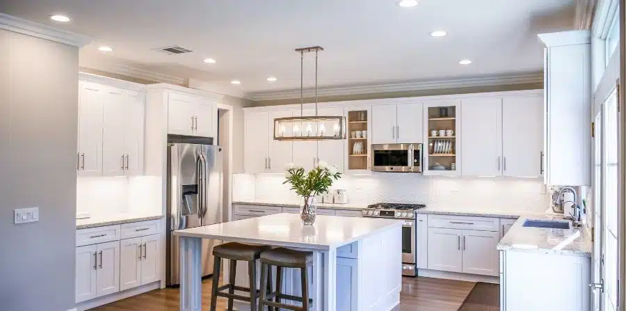 modern kitchen lighting renovation with white cabinets, pendant lights, and island bench