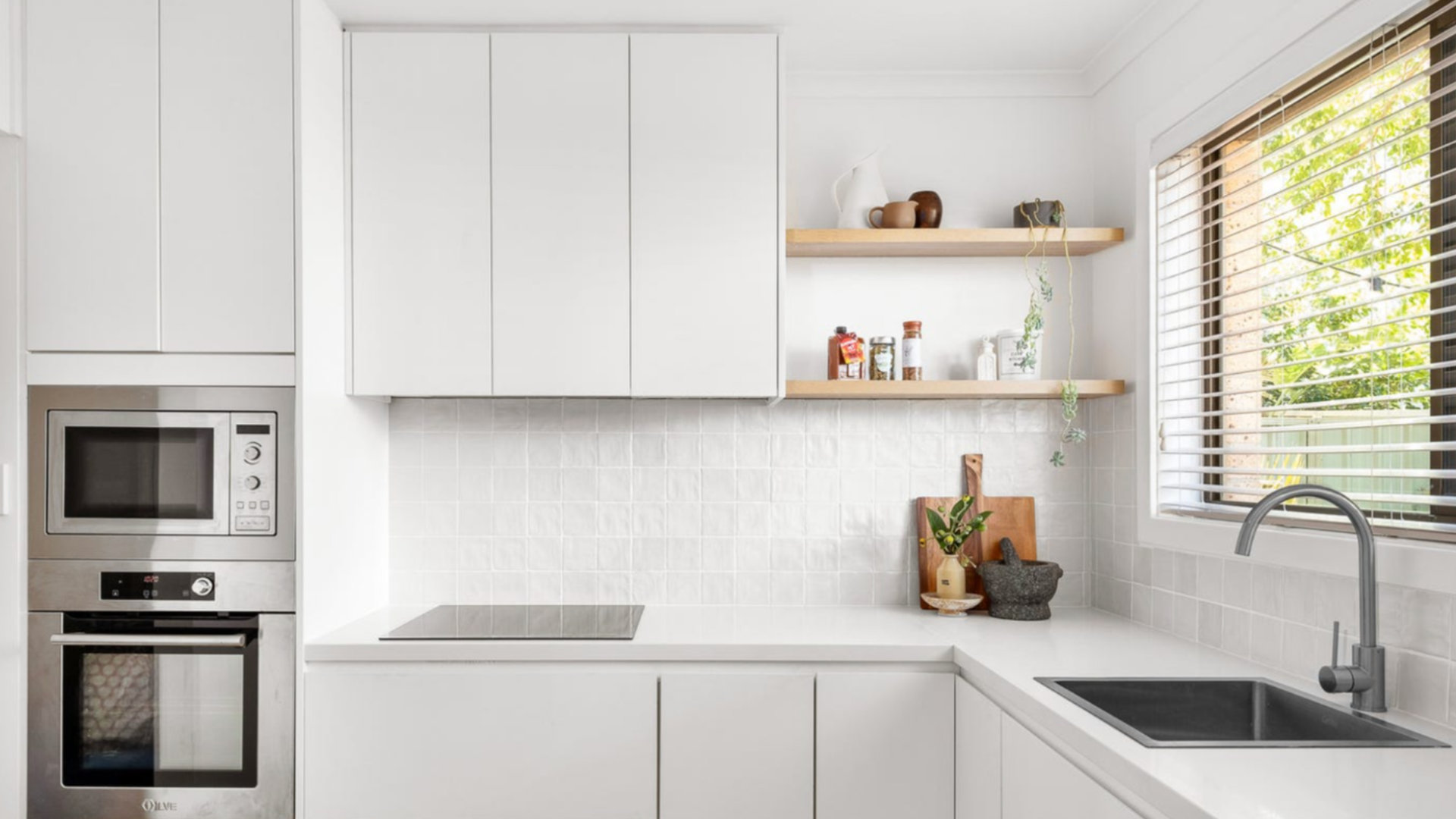 Modern kitchen design with white cabinets and wooden shelves – example of functional renovation layout.