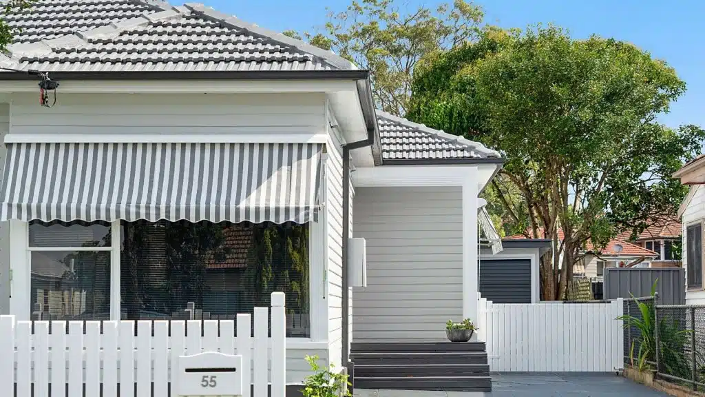 close up of renovated home front entrance with striped awnings and modern grey finish