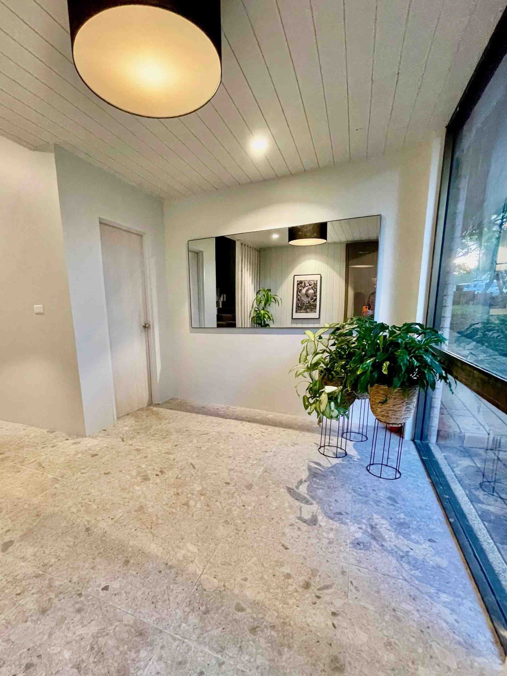 Stylish strata lobby after renovation with mirror and greenery