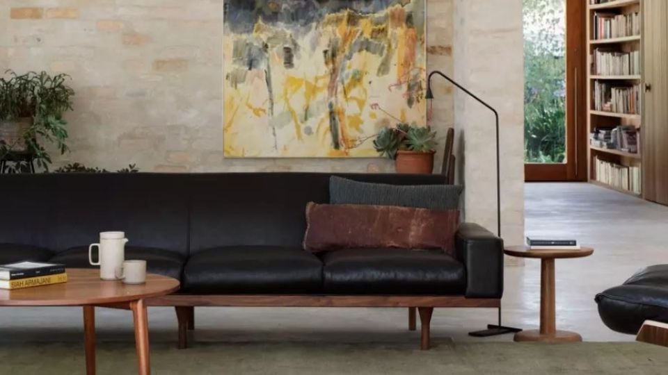Modern living room with black leather sofa and abstract art using dopamine design elements