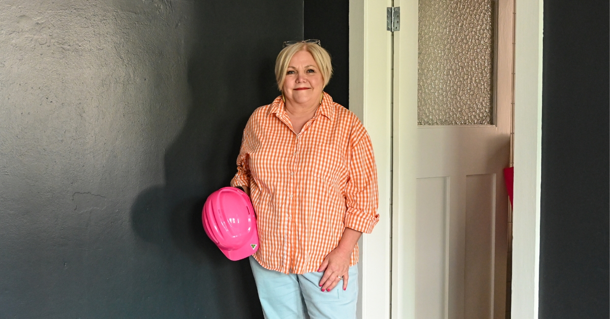 Bernadette Janson standing confidently with a pink hard hat, representing expert advice for women securing renovation finance after 50